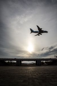 Low angle view of airplane flying against sky during sunset