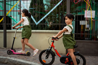 Side view of man riding push scooter on street