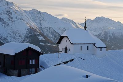 Snow covered houses and mountains against sky