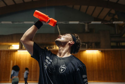 Male athlete pouring water on face from bottle at sports court