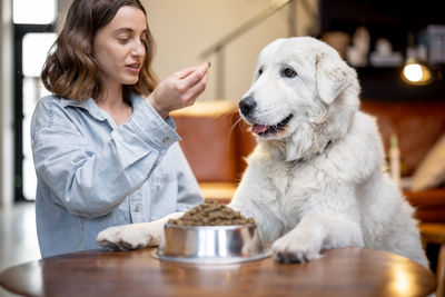 Full length of a woman with dog sitting on table