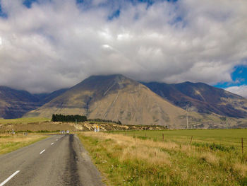 Road leading towards mountains against sky