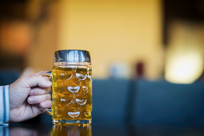 Cropped hand of man holding beer glass on table