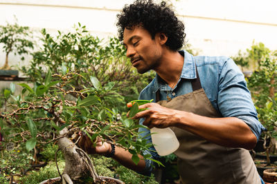 Young man looking away while holding plants