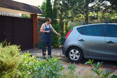 Side view of man standing by car