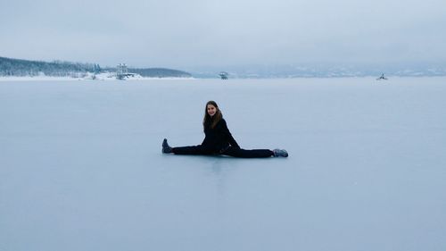 Young woman in snow against sky