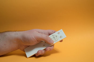 Close-up of human hand against orange background