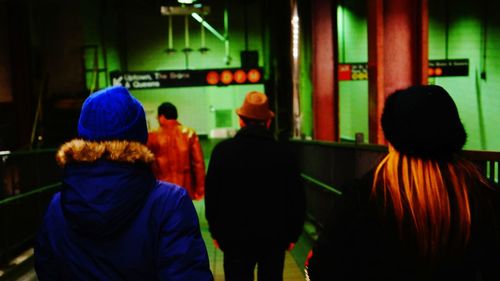 Rear view of people standing in illuminated city