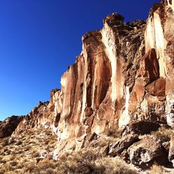 Low angle view of rock formation against clear blue sky