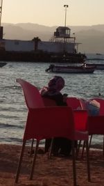 Rear view of man sitting on chair at beach