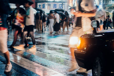 People on wet street in city