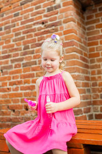 Cute girl standing against brick wall