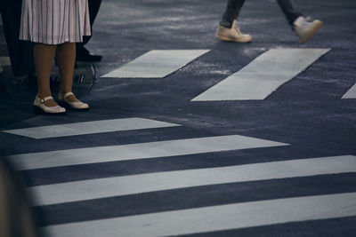 Low section of woman crossing road