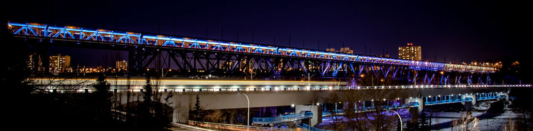 Illuminated bridge over river against sky at night