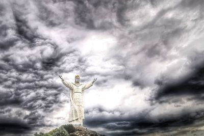 Low angle view of angel statue against cloudy sky