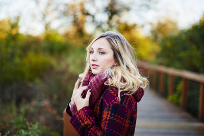 Portrait of young woman standing against tree