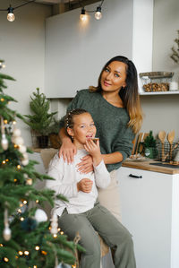 Stylish mom and daughter in homemade clothes eat christmas cookies in the kitchen
