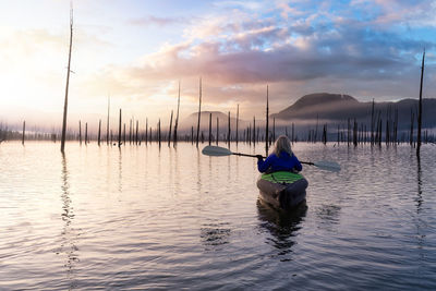 Rear view of man on sailboat in sea against sky