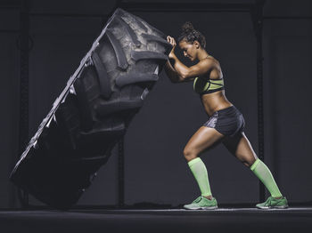 Young woman lifting up a tractor tyre