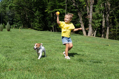 Portrait of young woman with dog on grassy field