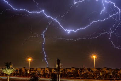 Lightning over illuminated buildings in city at night