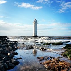 Lighthouse by sea against sky