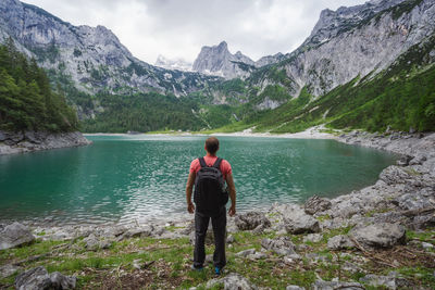 Man traveler enjoying view of dachstein peak mountains on a upper gosau lake. gosau, austria, europe