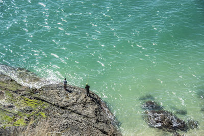 High angle view of men fishing by turquoise sea