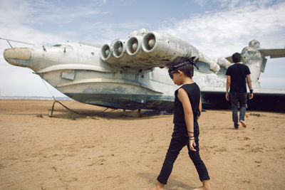 Family a boy and his father in rocker clothes walk at  ekranoplan plane by the sea in dagestan