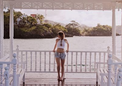 Full length of young woman standing on pier over lake