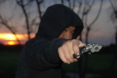 Man aiming with gun during sunset