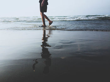 Low section of woman walking on beach