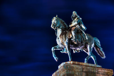 Low angle view of statues against sky at night
