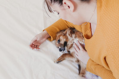 High angle view of woman with dog playing on bed at home