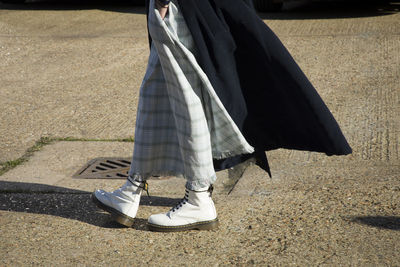 Low section of woman walking on road during sunny day