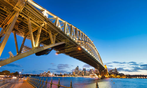 Low angle view of bridge over river against blue sky