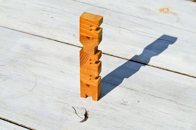 High angle view of stacked wooden text on table during sunny day