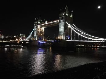 Illuminated suspension bridge over river at night