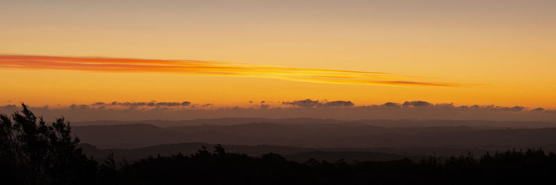 Scenic view of silhouette mountains against orange sky