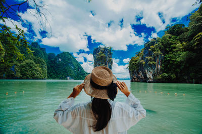 Rear view of woman with arms raised against sky