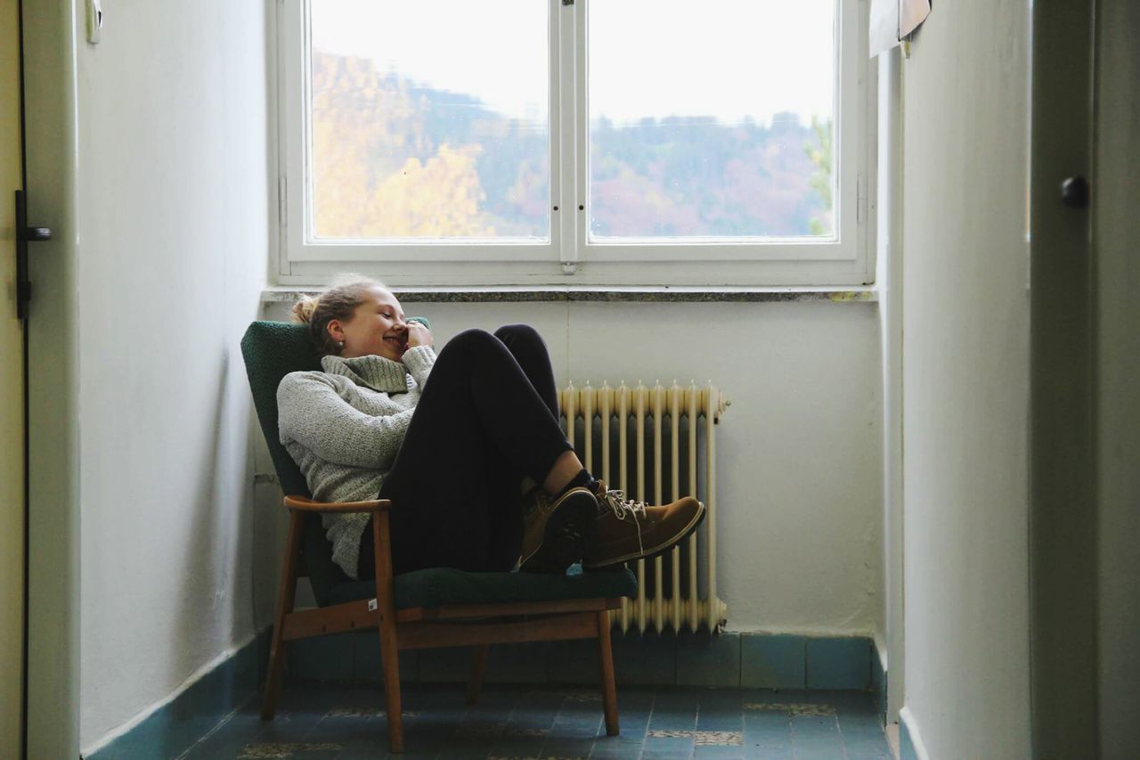 window, sitting, full length, indoors, one person, mature adult, radiator, adults only, people, relaxation, home interior, day, living room, domestic life, adult, one woman only