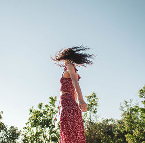 Woman standing by tree against sky