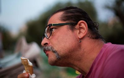 Close-up of thoughtful man looking away while holding ice cream outdoors