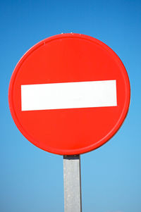 Close-up of road sign against blue sky