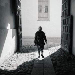 Rear view of man walking on footpath amidst buildings