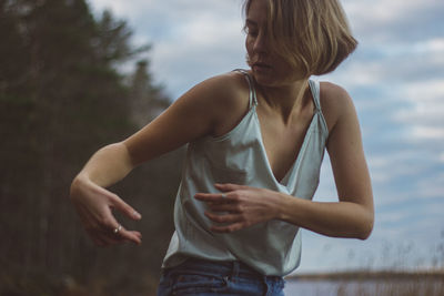 Close-up of beautiful woman dancing against cloudy sky