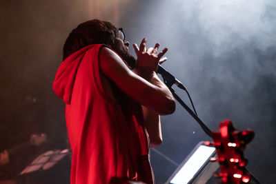 Side view of man singing song at stage