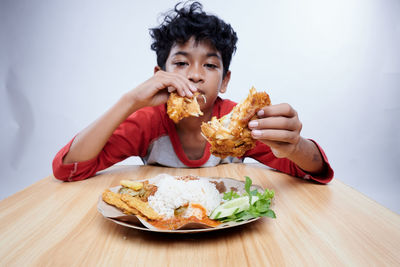 Portrait of young woman eating food on table