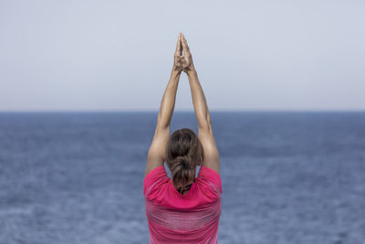 Rear view of woman standing at beach against clear sky