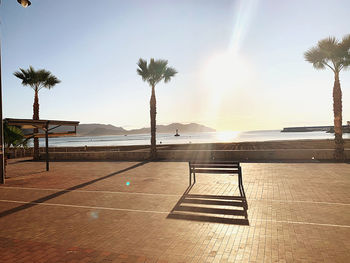 Empty chairs by swimming pool against sky
